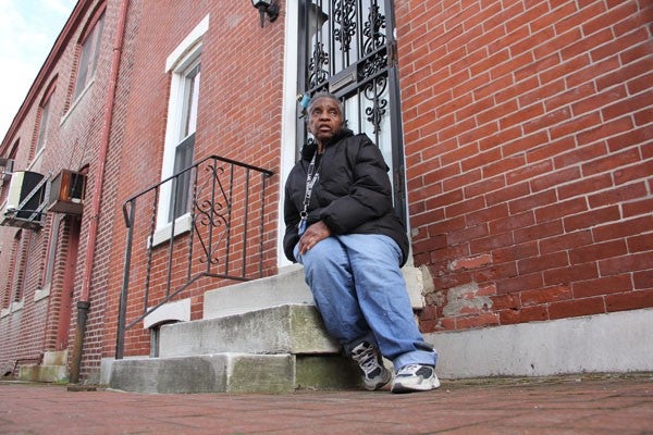 A woman sits on the concrete steps in front of her Philadelphia rowhome