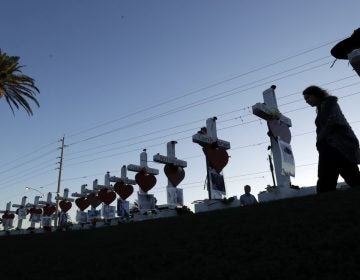 A woman passes crosses set up to honor those killed during the mass shooting in Las Vegas.