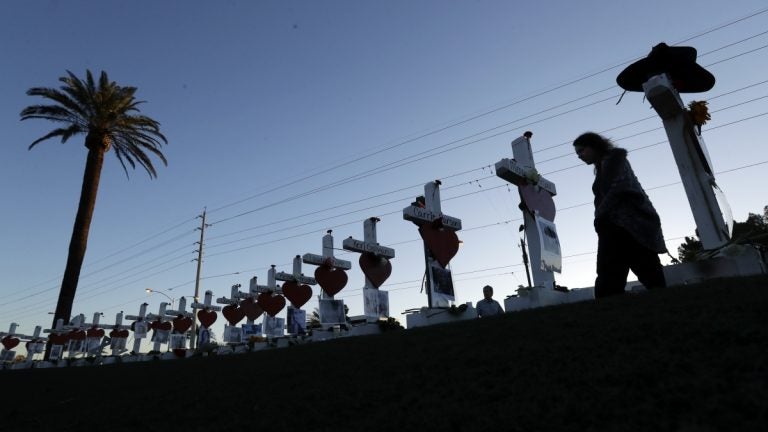 A woman passes crosses set up to honor those killed during the mass shooting in Las Vegas.