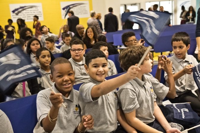 Mastery Cramer Hill Elementary school students Marvell Rivera and Jadhiel Tineo wave flags at the school dedication in Camden Tuesday morning. (Kimberly Paynter/WHYY)