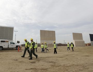 People pass border wall prototypes as they stand near the border with Tijuana, Mexico, Thursday, Oct. 19, 2017, in San Diego.