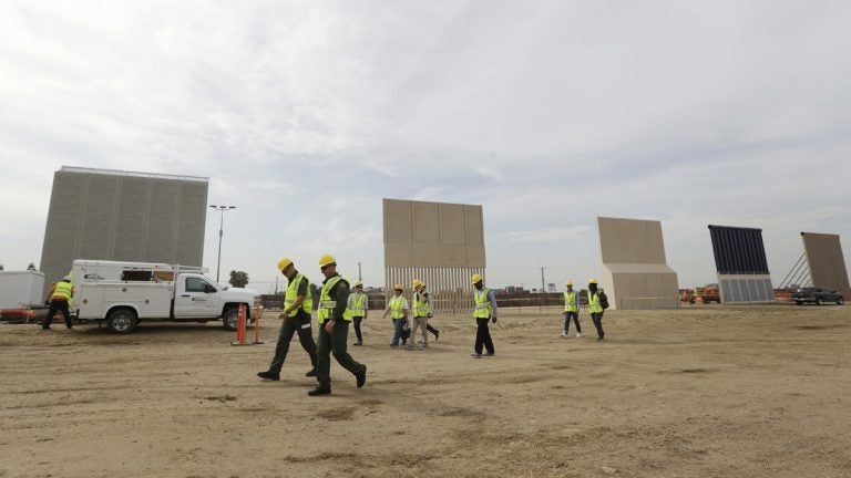 People pass border wall prototypes as they stand near the border with Tijuana, Mexico, Thursday, Oct. 19, 2017, in San Diego.