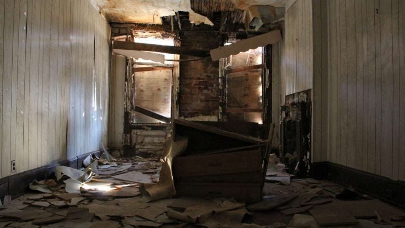 Shafts of light penetrate the boarded windows in the living room of 753 Walnut St. (Emma Lee/WHYY)