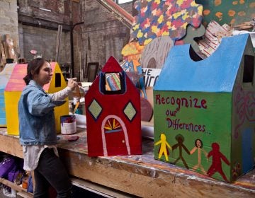 Spiral Q apprentice Laura Beery paints houses for Peoplehood parade participants to wear on Saturday. (Kimberly Paynter/WHYY)