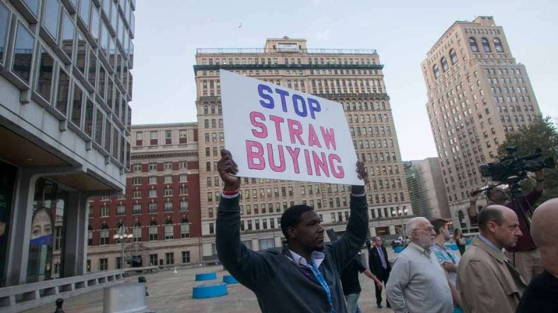 Michael Cogbill, an organizer for Ceasefire PA, held a sign against straw purchasing guns at a vigil for victims of Sunday night's mass shooting in Las Vegas.