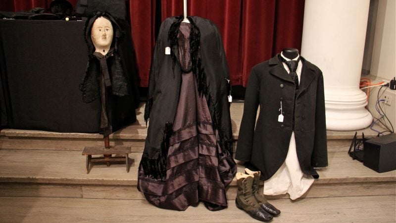 Black formal suit and dress represent mourning clothing of the 19th century.