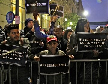 People holding Free Meek Mill signs crowd up to a barrier outside the center for criminal justice