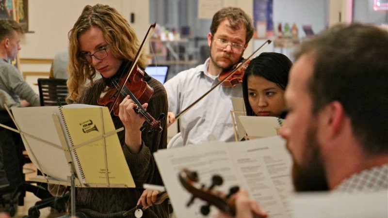 Dragging a tattered bow across two strings on a bridgeless violin, Schuyler Thum (left)prepares for his performance in 