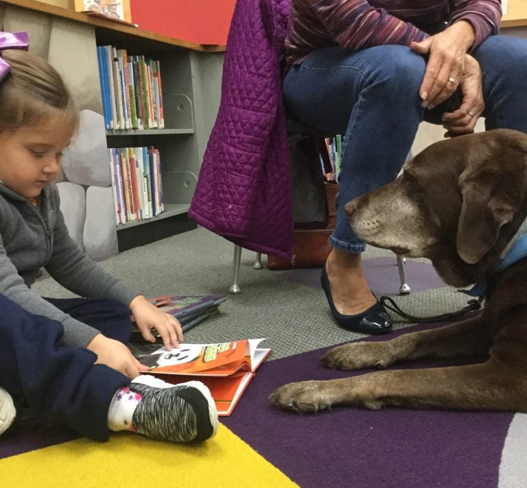 Mia Zelmanoff reads a book to Rocky at the Torresdale library in Northeast Philly.