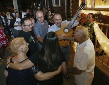 Cousin of the bride, Vincenzo Longo, plays the guitar as a crowd gathers in the street outside the decorated home of Susan and Larry Longo during the Italian wedding serenade for their daughter Stephanie Longo, Saturday, Oct. 7, 2017, in Philadelphia, Pa.  An Italian wedding tradition is alive and well in south Philadelphia, where young couples are transforming something old into something new with their take on the wedding serenade. (Mel Evans/AP Photo)