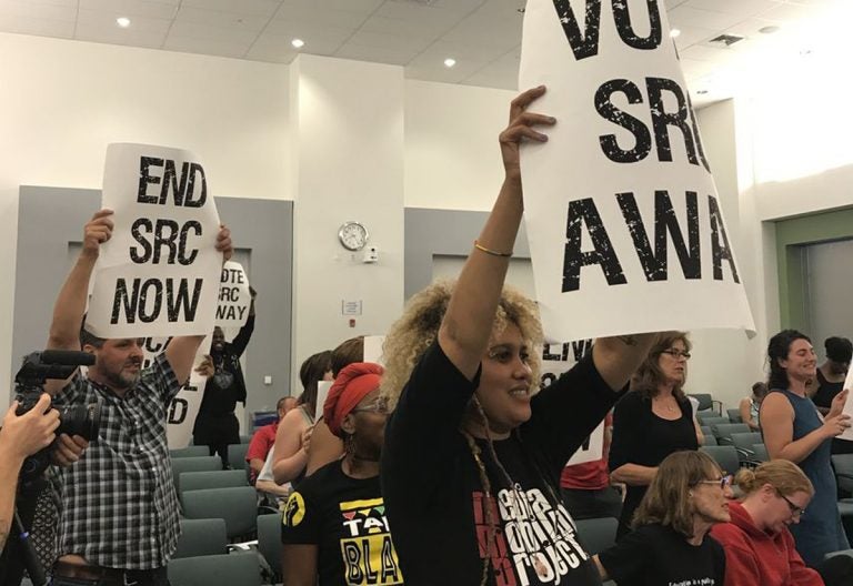 At the June 15 School Reform Commission meeting, demonstrators carried signs calling for the SRC to vote itself out of existence and return the school district to city control. (David Hornbeck/The Notebook)