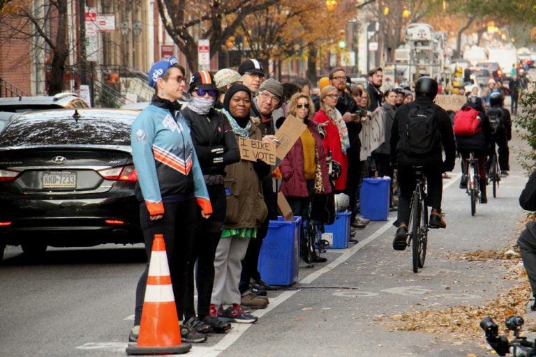 Protesters demanding protected bike lanes form a human barrier on Nov. 28, stretching for two blocks along Spruce Street near 11th Street, where a cyclist was killed by a garbage truck the previous morning. (Emma Lee/WHYY)