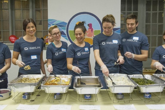 Volunteers from WebLinc serve refugees Thanksgiving dinner. (Jonathan Wilson for WHYY)