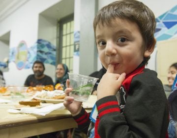 Hasib licks his fingers during the Annual Thanksgiving Celebration dinner. (Jonathan Wilson for WHYY)