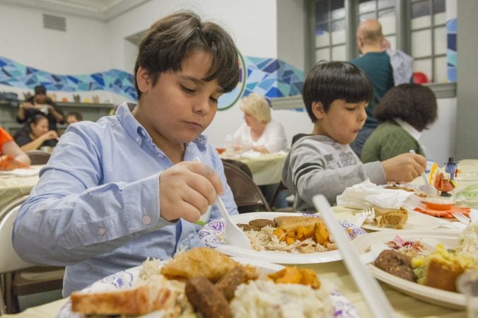Iraqi refugees Ali, left and his brother Hayder enjoy their Thanksgiving dinner. (Jonathan Wilson for WHYY)