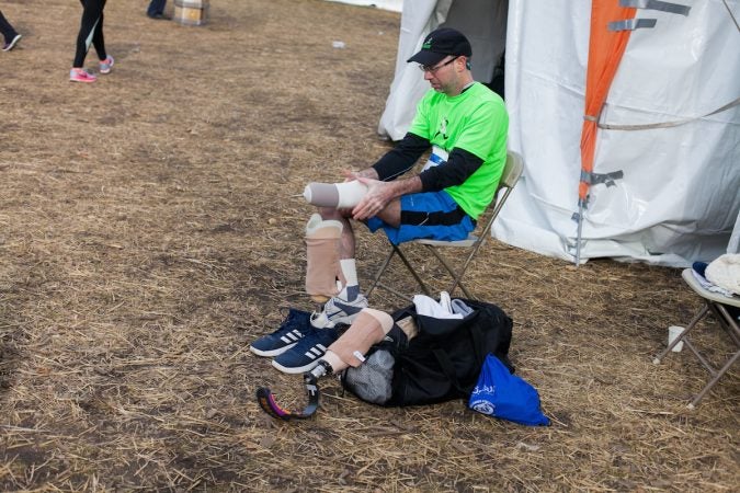 Evan Freiberg changes his prosthetic before the Rothman Institute 8k Saturday. The 43-year-old is diagnosed with leiomyosarcoma, a form of cancer, and competed after losing the bottom portion of his left leg to the disease. (Brad Larrison for WHYY)