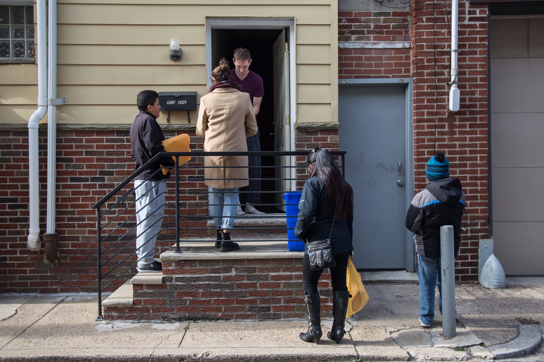 A group of people hand out literature to a man at the door of a South Philadelphia row home