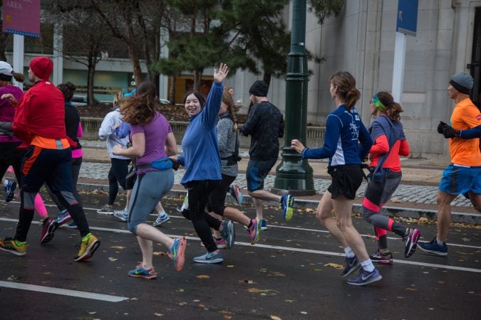 A runner waves to her family as she runs in the 23rd annual Philadelphia Marathon on Sunday November 19th, 2017.