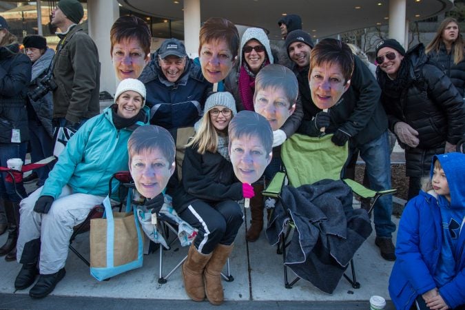 Scott Conaway (top left) holds up a photo of his wife's face with his family. Ingrid Conaway finds the parade too cold, so this year the family brought her in spirit. (Emily Cohen for WHYY)