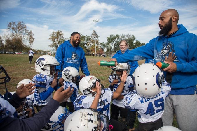 Rickey Duncan, left, helps pump up his 6U team during the half-time of their game.