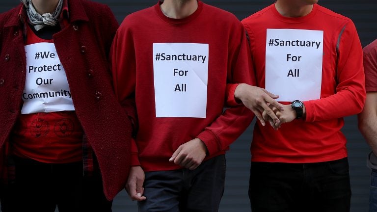 Protesters stand arm-in-arm as they block an entrance to the U.S. Immigration and Customs Enforcement office in San Francisco, Calif., on May 1. San Francisco sued the Trump administration over its threats to cut grant money to cities that don't fully cooperate with federal immigration authorities. (Justin Sullivan/Getty Images)