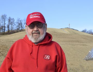 Washington County resident Frank Brownlee stands in his backyard, where a rig on the hill behind him is drilling natural gas wells. (Amy Sisk/StateImpact Pennsylvania)