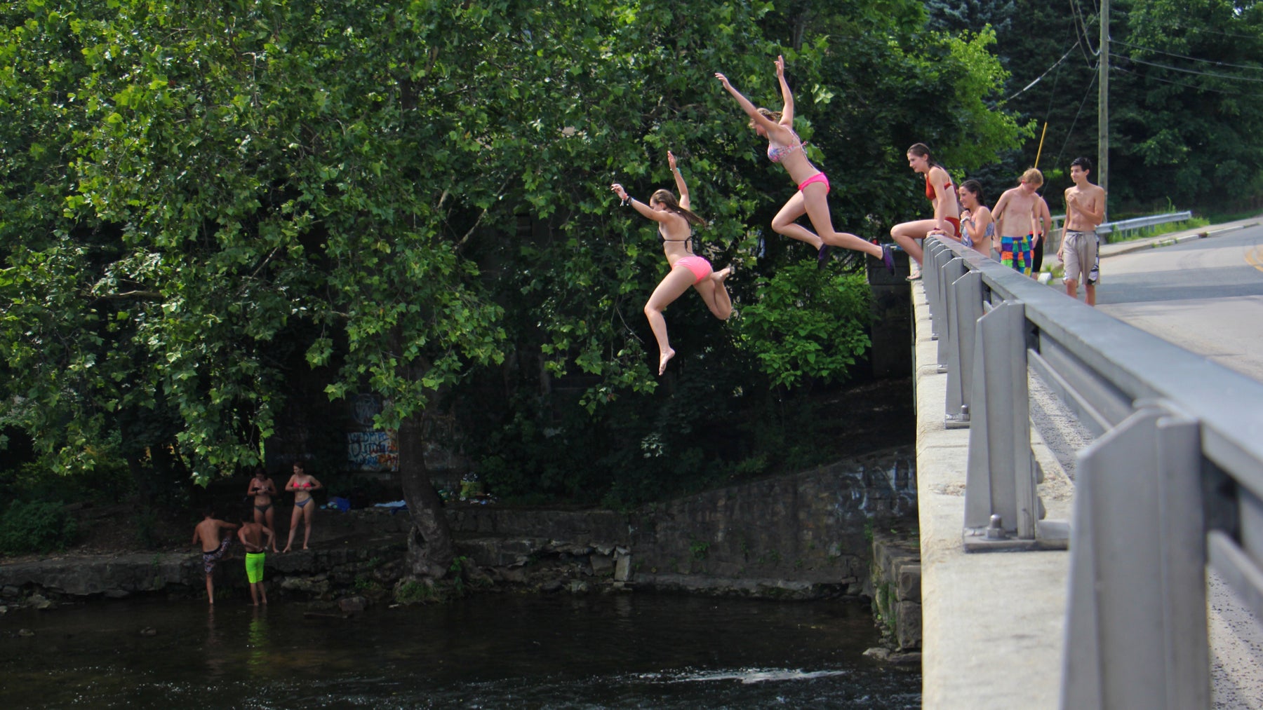 Teenagers take turns jumping into the Musconetcong river just below the Asbury Mill Dam. 