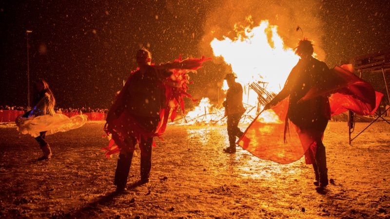 Revelers dance dressed in folklore costumes in front of the burning phoenix at the 14th Annual Firebird Festival in Phoenixville. (Emily Cohen for WHYY)