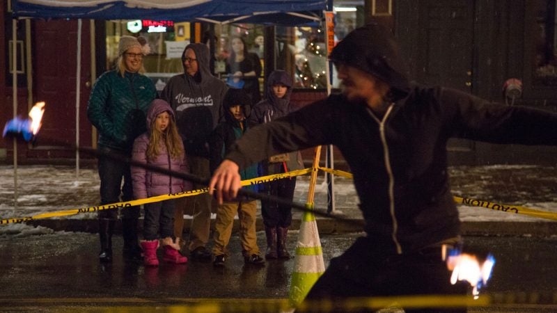 A family watches as Chris Tamburro spins fire on Bridge Street at the 14th Annual Firebird Festival in Phoenixville. (Emily Cohen for WHYY)