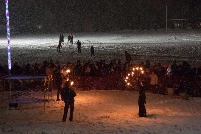 Spectators are entertained by fire spinners while waiting to watch the 30-foot-tall wooden phoenix set ablaze at the 14th Annual Firebird Festival in Phoenixville. (Emily Cohen for WHYY)