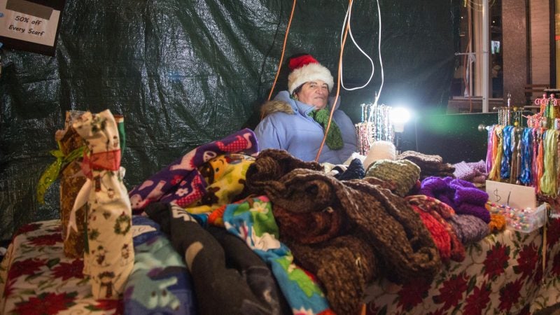 Violeta Comanuic tries to stay warm as she sells her knit goods at the 14th Annual Firebird Festival in Phoenixville, Pennsylvania. (Emily Cohen for WHYY)
