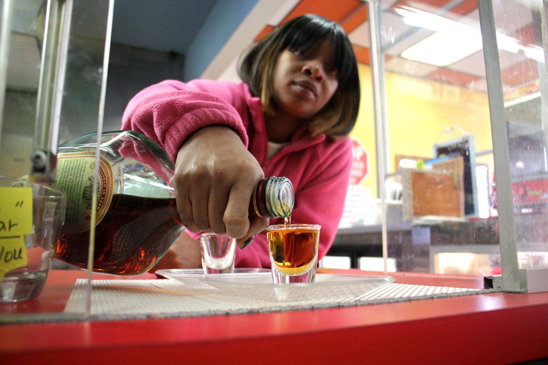 After opening a sliding plexiglass door, Nasifa Erwin pours a shot for a customer at Olney Steak and Beer on North Broad Street. 