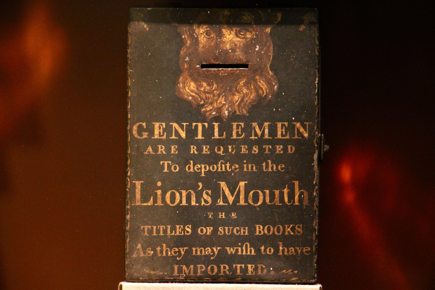 A relic from the early days of Benjamin Franklin's Library Company , a box for requested titles, remains on the shelf behind a layer of plexiglass. 