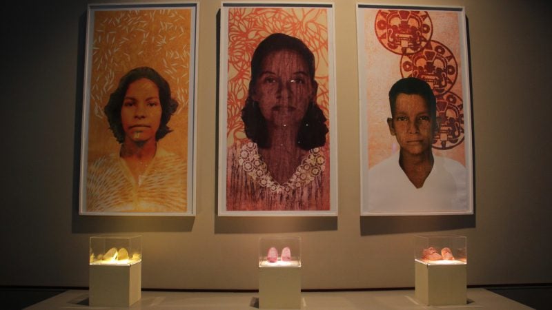 Michelle Angela Ortiz pays homage to family members with a trio of works at the Pennsylvania Convention Center. Each portrait is accompanied by a pair of shoes that represents their journey. (Emma Lee/WHYY)