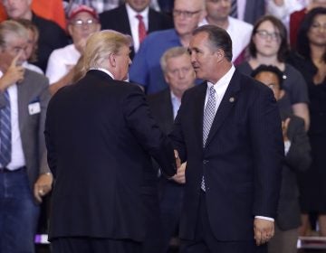 President Donald Trump shakes hands with Arizona Representative Trent Franks during a rally at the Phoenix Convention Center, Tuesday, Aug. 22, 2017, in Phoenix.