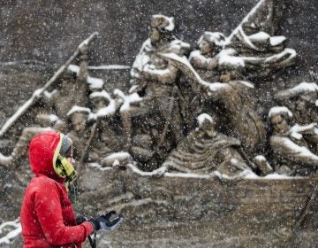 A person walks during a snowstorm past a sculpture of General George Washington crossing the Delaware River mounted on the Museum of the American Revolution in Philadelphia, Friday, Dec. 15, 2017. (AP Photo/Matt Rourke)