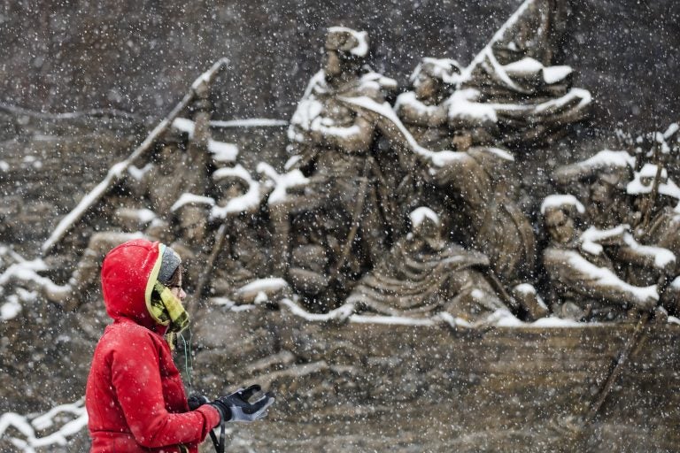 A person walks during a snowstorm past a sculpture of General George Washington crossing the Delaware River mounted on the Museum of the American Revolution in Philadelphia, Friday, Dec. 15, 2017. (AP Photo/Matt Rourke)