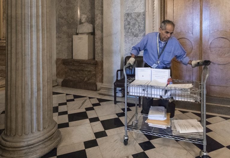 After senators worked past midnight to pass the Republican tax bill, Walter Arandia distributes copies of the daily legislative calendar before lawmakers return, on Capitol Hill, in Washington, early Wednesday, Dec. 20, 2017.