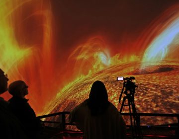 In this Wednesday, Dec. 6, 2017 photo, people watch interstellar bodies move through space during a media preview at the planetarium at Liberty Science Center in Jersey City, N.J. The  newly refurbished planetarium is the largest in the western hemisphere and uses ten advanced projectors to produce an 8K resolution. It opens to the public on Saturday, Dec. 9, 2017. (Seth Wenig/AP Photo)