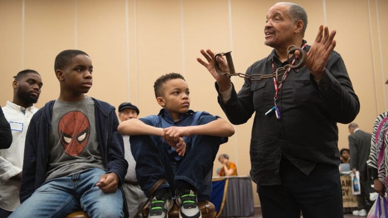 J. Justin Ragsdale holds up antique slave shackles during a demonstration on the conditions inside slave ships during the 2017 Black History and Culture Showcase in Philadelphia