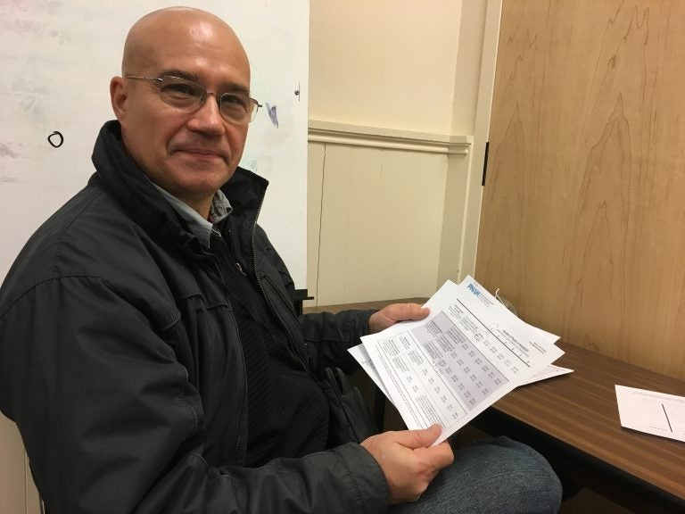 Gokhan Ozagacli looks over paperwork Thursday after enrolling for health insurance with the help of Pennsylvania Health Access Network. (Anne Hoffman/ for WHYY)