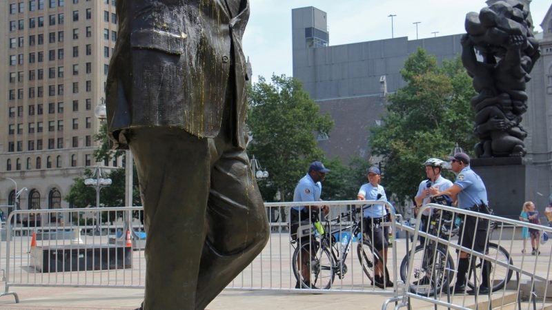 Philadelphia police stand guard over the Frank Rizzo statue at Thomas Paine Plaza after it was egged by vandals. (Emma Lee/WHYY)