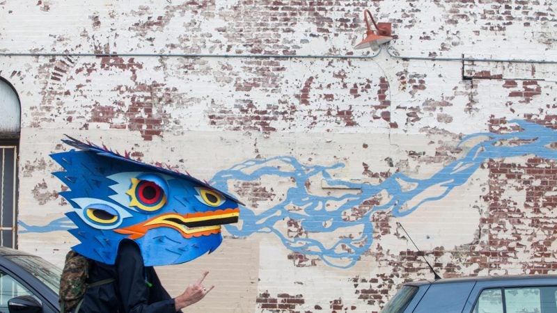 Rob Leef rides down Norris Street in his Reptilikus costume during the Philadelphia Kinetic Sculpture Derby. (Brad Larrison for NewsWorks)