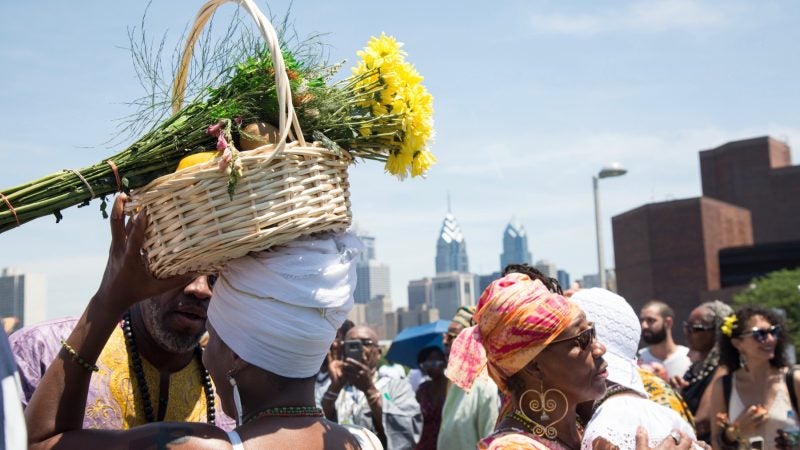 A woman carries offerings for the river goddess Oshun at the begining of the Philadelphia Odunde Festival. (Emily Cohen for WHYY)