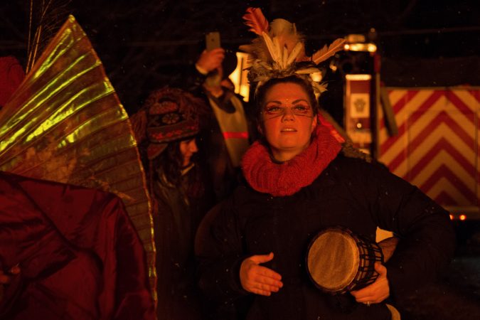 Revelers dance and drum dressed in folklore costumes as they watch the phoenix burning at the 14th Annual Firebird Festival in Phoenixville. (Emily Cohen for WHYY)