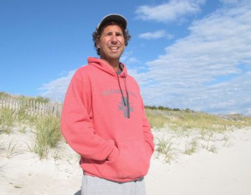 This Oct. 26, 2017 photo shows Dominick Solazzo, president of the Midway Beach Condominium Association on the beach in front of the 25-foot-tall dunes his members built. (AP Photo/Wayne Parry)