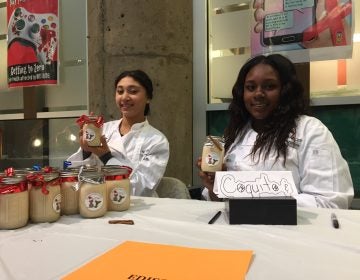 Keilina Collazo (left) and Elima Patterson, students at Edison High School, offer their homemade coquito for sale. (Avi Wolfman-Arent/WHYY). 