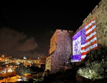 The American and Israeli flags are on display Wednesday on the walls of the Old City of Jerusalem. President Trump announced that the U.S. will view Jerusalem as the capital of Israel, and he ordered the State Department to 