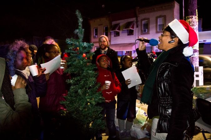 Asteria Vives (right) and the girls club from the Lenfest Center sing holiday carols at 2nd and Indiana Streets in Kensington. (Kimberly Paynter/WHYY)