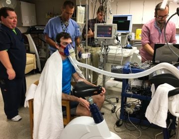 Volunteer Greg Ruegsegger is outfitted with monitors, a catheter threaded into a vein and a mask to capture his breath in an experiment run by Joyner to measure human performance. (Richard Harris/NPR)